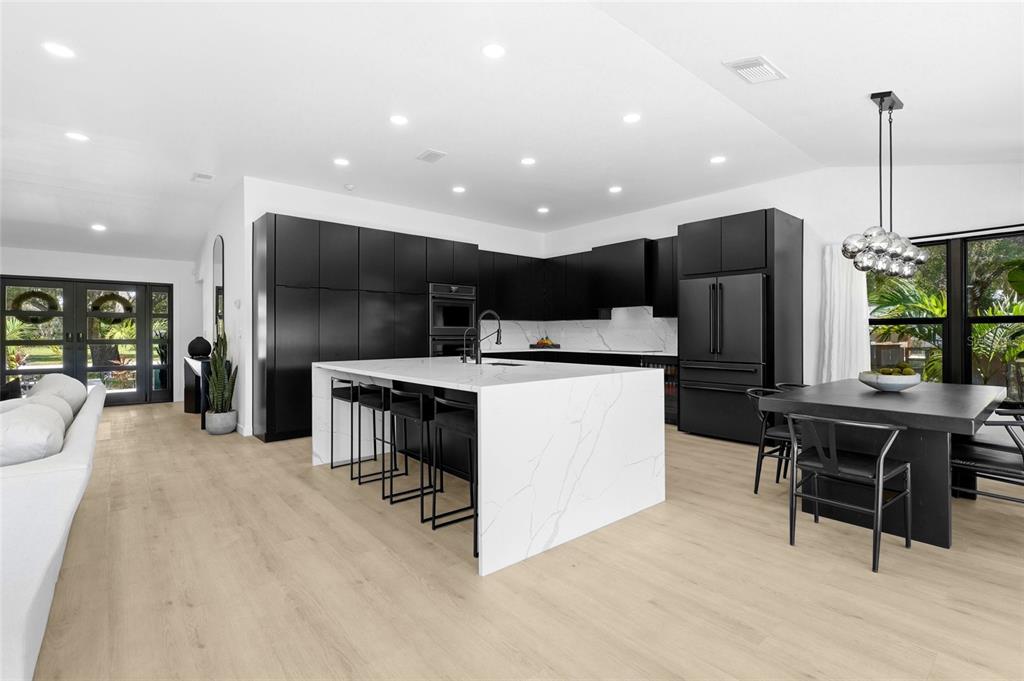 A modern living room features a dark fireplace wall, light wood floors, and large glass doors — 906 136TH STREET E, BRADENTON, FL