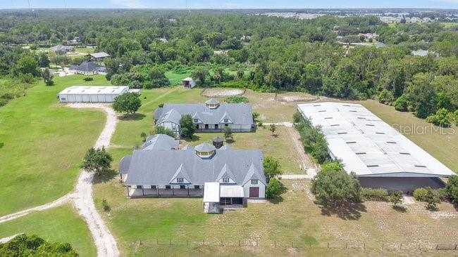 An aerial view shows a large equestrian property with multiple barns and a central building — 2121 DRESSAGE COVE, CHULUOTA, FL