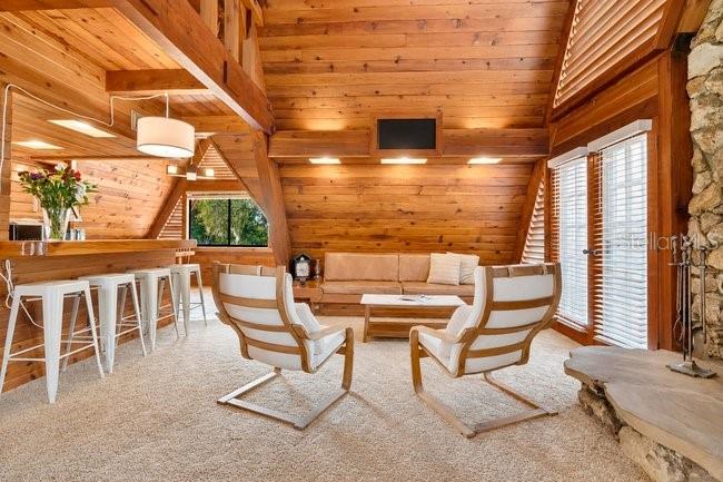 A rustic living room features wood-paneled walls, two white chairs, and a bar area — 2121 DRESSAGE COVE, CHULUOTA, FL