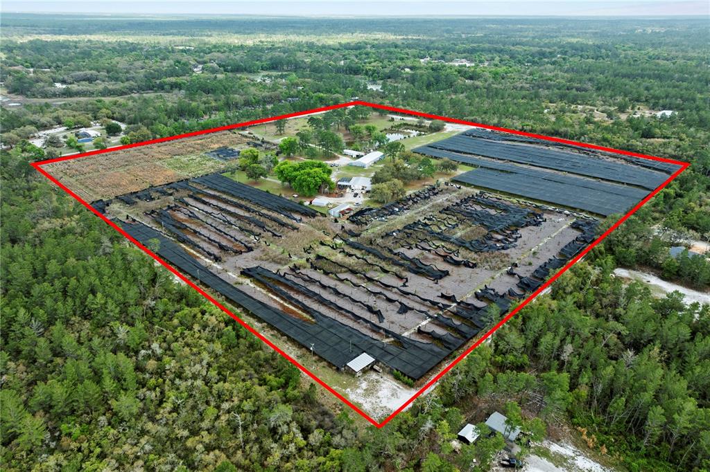An aerial view shows a large, rectangular property featuring agricultural shade structures and outbuildings — 40945 BEACH ROAD, EUSTIS, FL