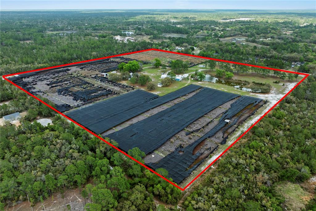 An aerial view shows a large rural property featuring extensive black shade cloth structures — 40945 BEACH ROAD, EUSTIS, FL