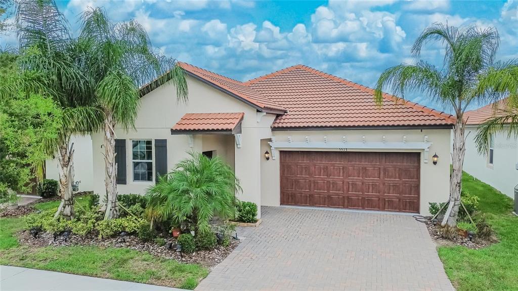 A single-story house with a tiled roof, a two-car garage, and palm trees in front — 5513 LITTLE PATH DRIVE, WIMAUMA, FL
