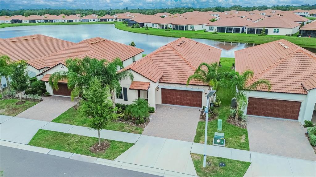 An aerial view shows three suburban houses with terracotta tile roofs and paved driveways — 5513 LITTLE PATH DRIVE, WIMAUMA, FL