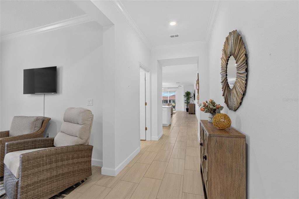 A hallway with light tile flooring leads from a living area toward a kitchen — 5513 LITTLE PATH DRIVE, WIMAUMA, FL