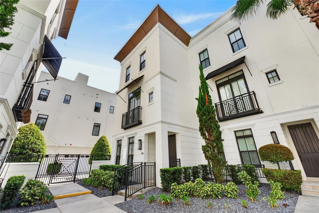 A low-angle exterior view of a modern white three-story townhouse with black metal balconies — 636 MARIPOSA STREET, ORLANDO, FL