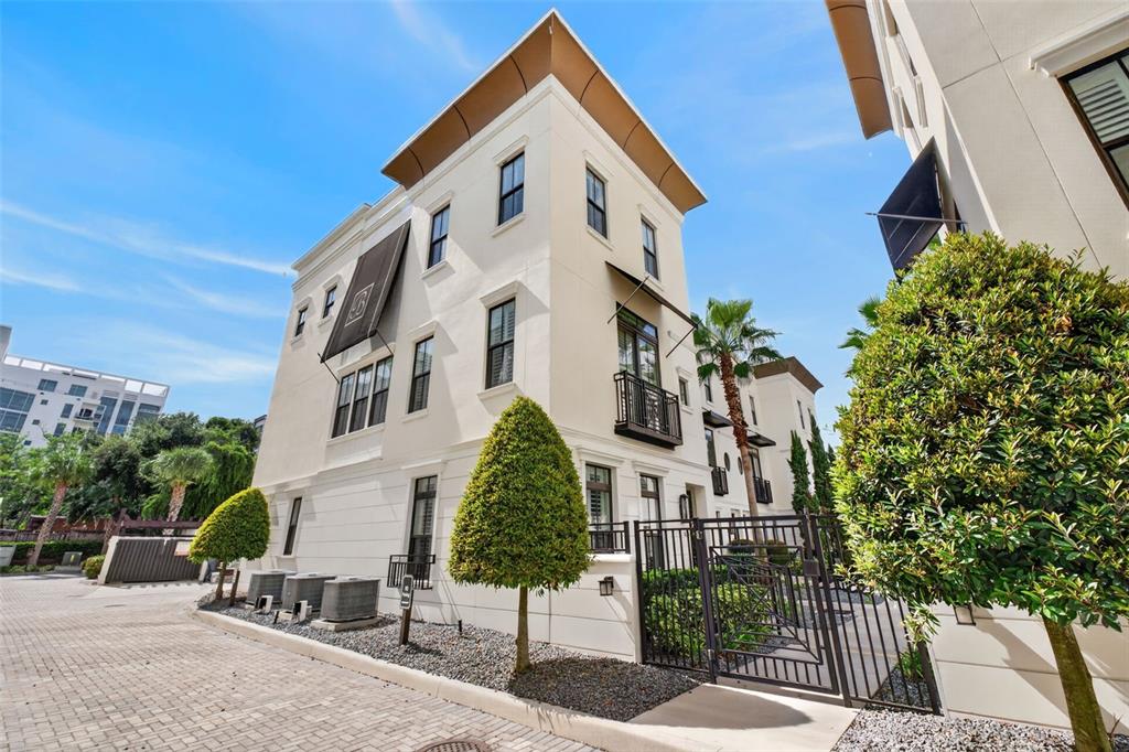 A three-story cream-colored townhouse with black metal balconies and a gated side entrance — 636 MARIPOSA STREET, ORLANDO, FL