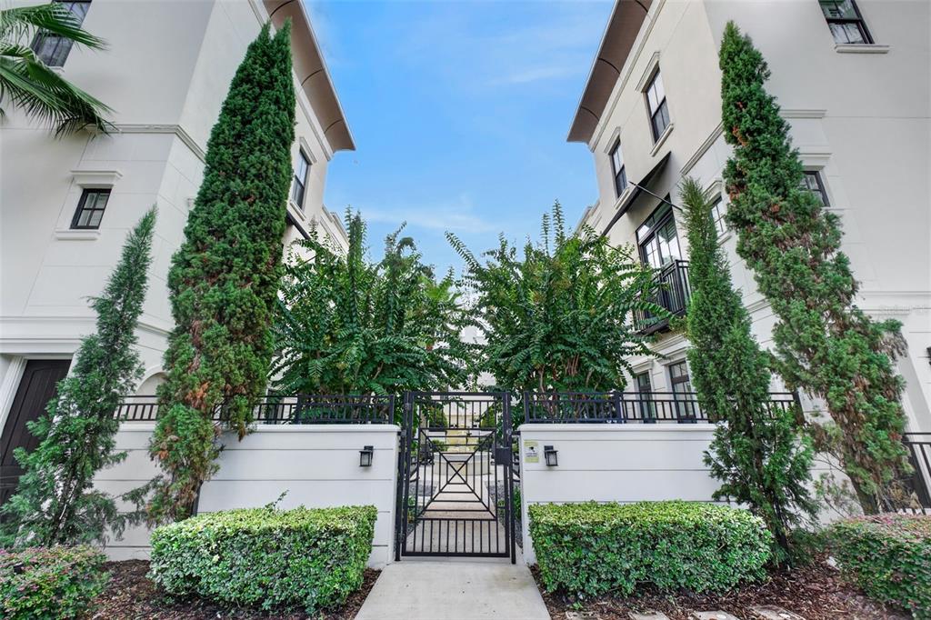 A gated entrance leads to a courtyard between two white multi-story residential buildings — 636 MARIPOSA STREET, ORLANDO, FL