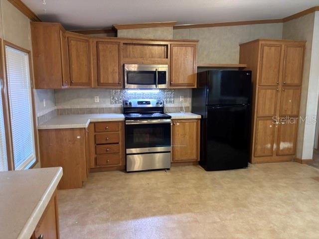 A kitchen features wood cabinets, stainless steel appliances, and a black refrigerator — 13270 NW 3RD TERRACE, TRENTON, FL
