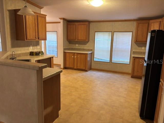 A kitchen features light wood cabinets, laminate countertops, and a black refrigerator — 13270 NW 3RD TERRACE, TRENTON, FL