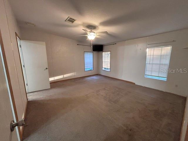 An empty bedroom features beige carpeting, white walls, a ceiling fan, and two windows — 13270 NW 3RD TERRACE, TRENTON, FL