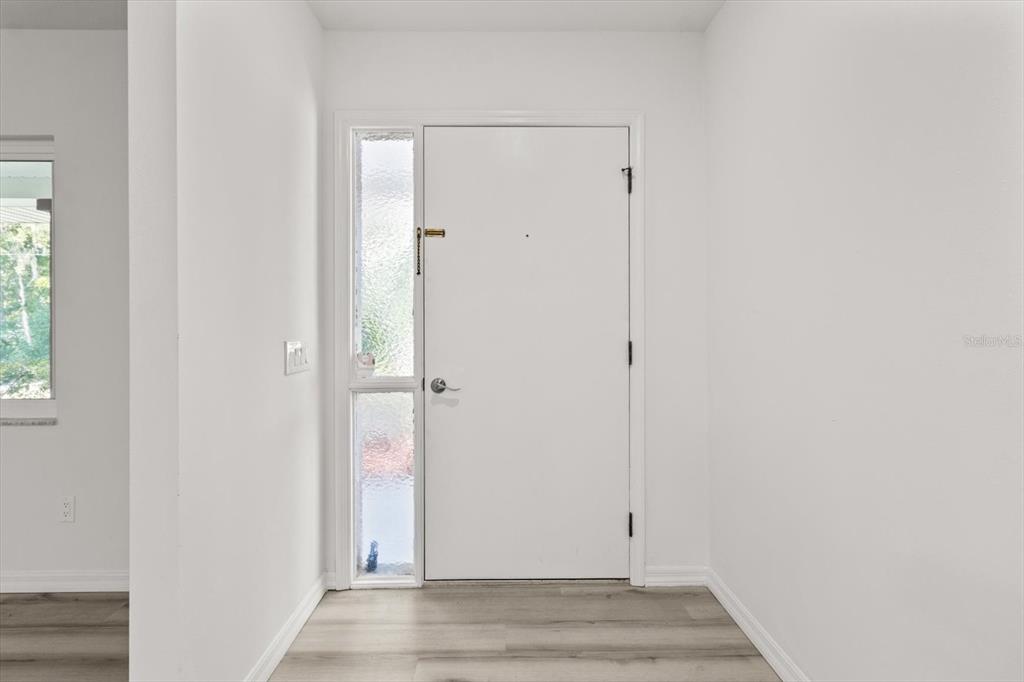 An entryway features a white front door with a side light and light wood flooring — 1255 S ESTATE POINT, INVERNESS, FL