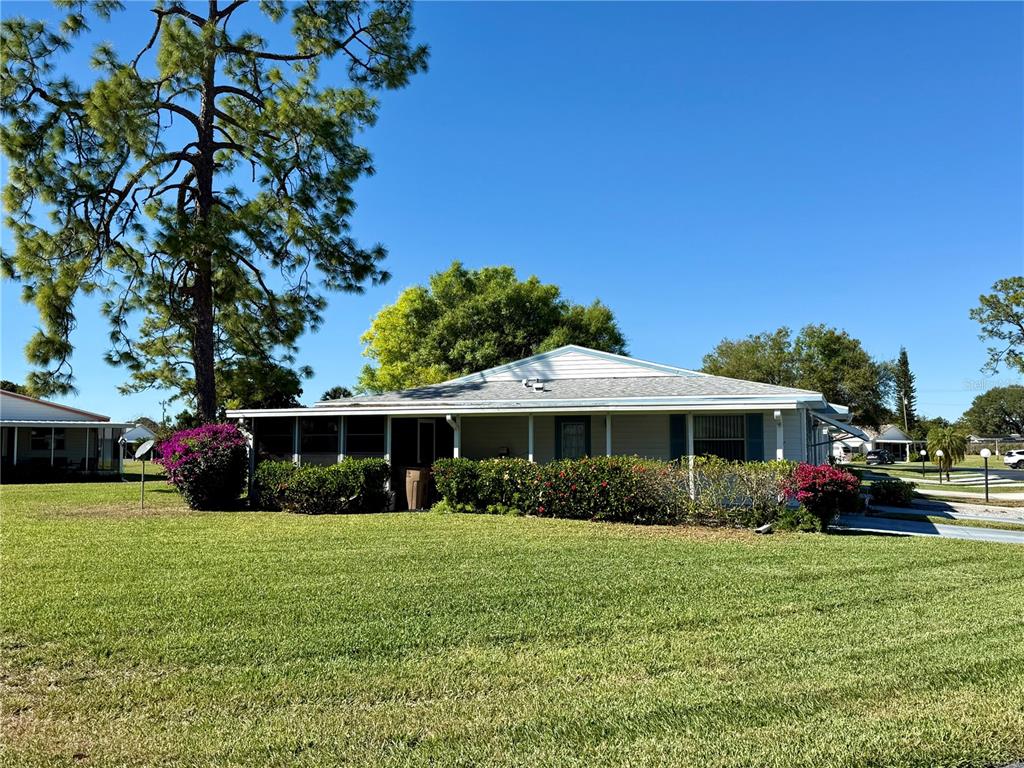 A single-story house with a white exterior, a covered porch, and a large front lawn — 7 DESERT CANDLE CIRCLE, LEHIGH ACRES, FL