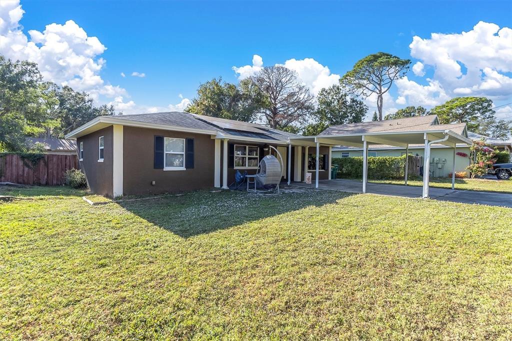 A brown single-story house with a white-trimmed carport and a large grassy front yard — 1797 RAINBOW BOULEVARD, CLEARWATER, FL