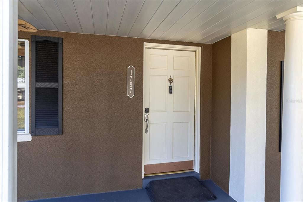 A white front door with a house number plaque sits on a covered porch — 1797 RAINBOW BOULEVARD, CLEARWATER, FL