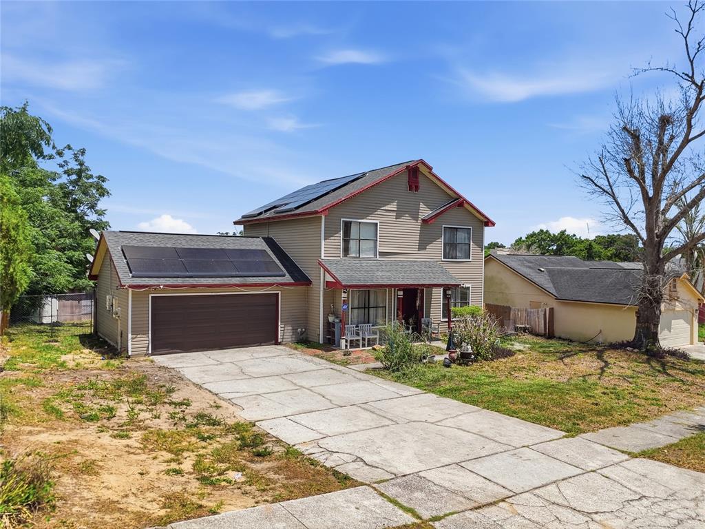 A two-story house with tan siding, a garage, and solar panels on the roof — 3027 QUEENSGATE ROAD, ORLANDO, FL