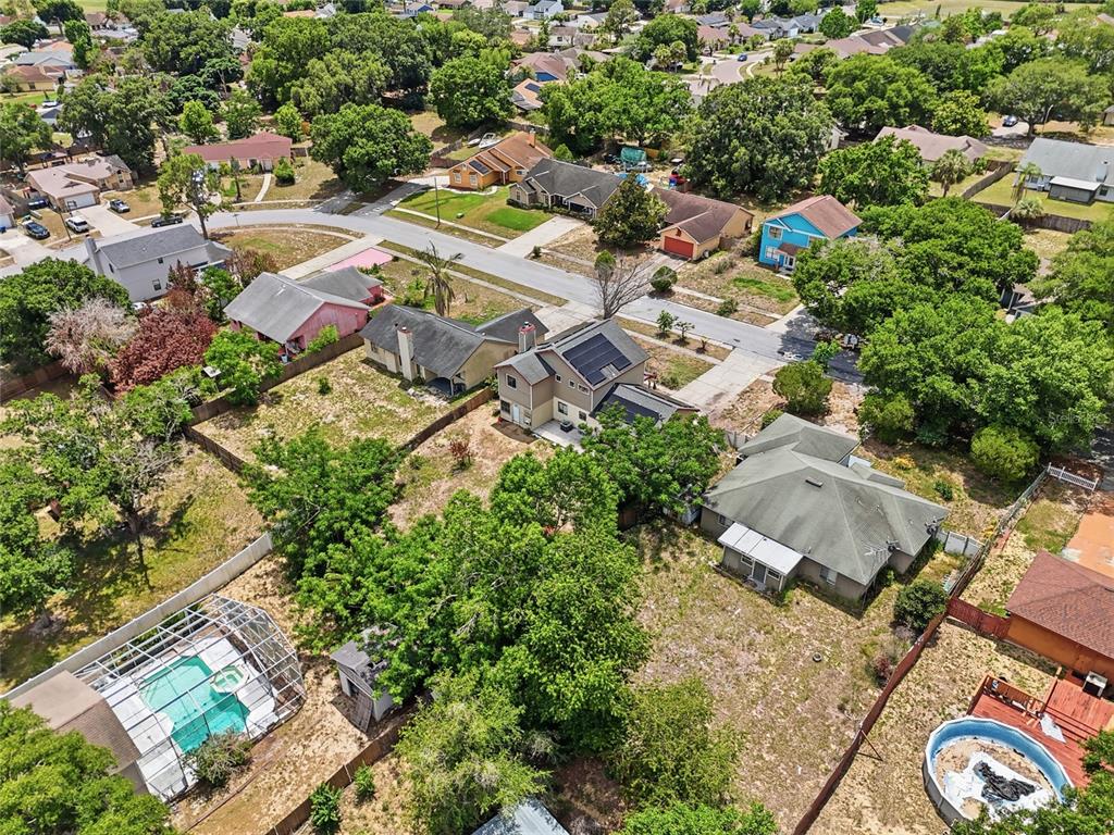 An aerial view shows suburban houses with yards, swimming pools, and tree-lined streets — 3027 QUEENSGATE ROAD, ORLANDO, FL