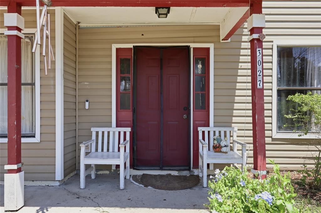 A front porch features a red door, two white benches, and tan vinyl siding — 3027 QUEENSGATE ROAD, ORLANDO, FL