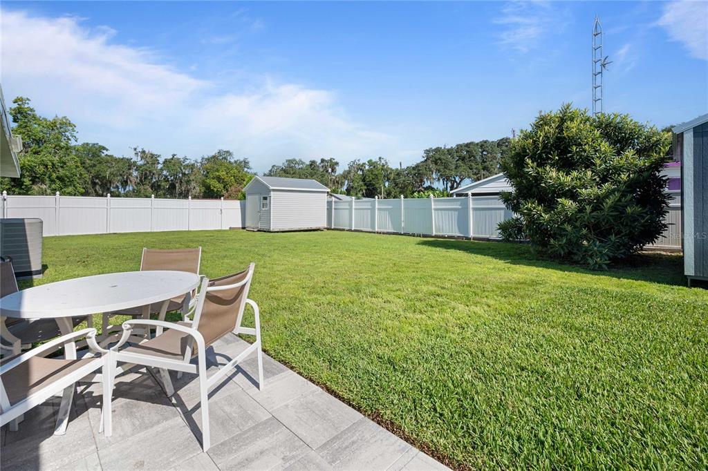 A backyard features a patio with a table and chairs, a shed, and a white fence — 1056 CR 463, LAKE PANASOFFKEE, FL