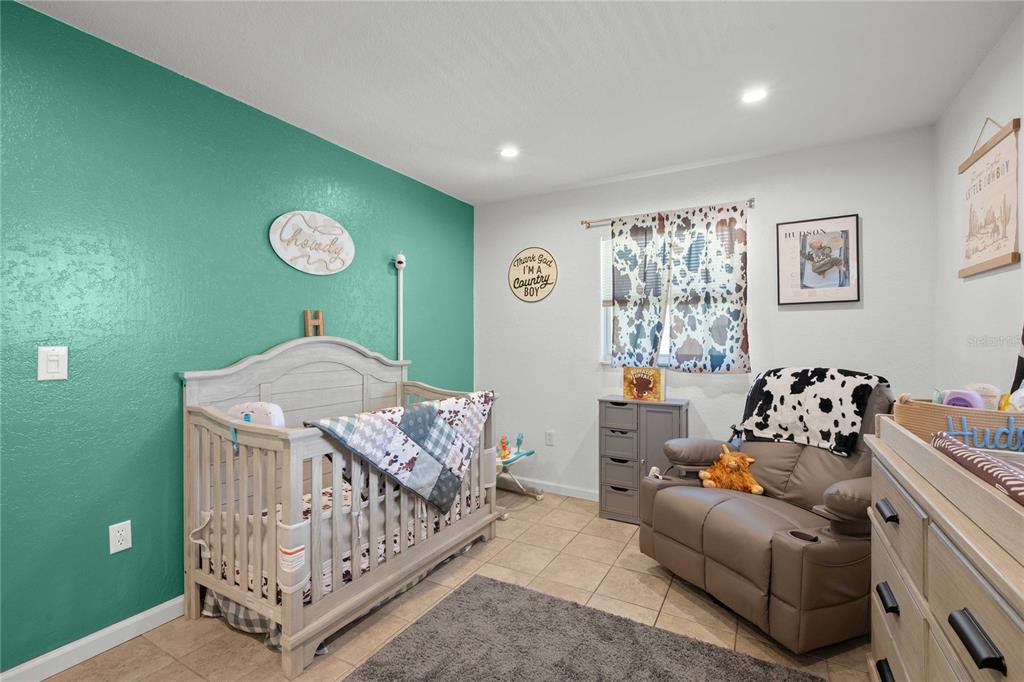 A nursery features a crib, a recliner, and a teal accent wall with western-themed decor — 1056 CR 463, LAKE PANASOFFKEE, FL