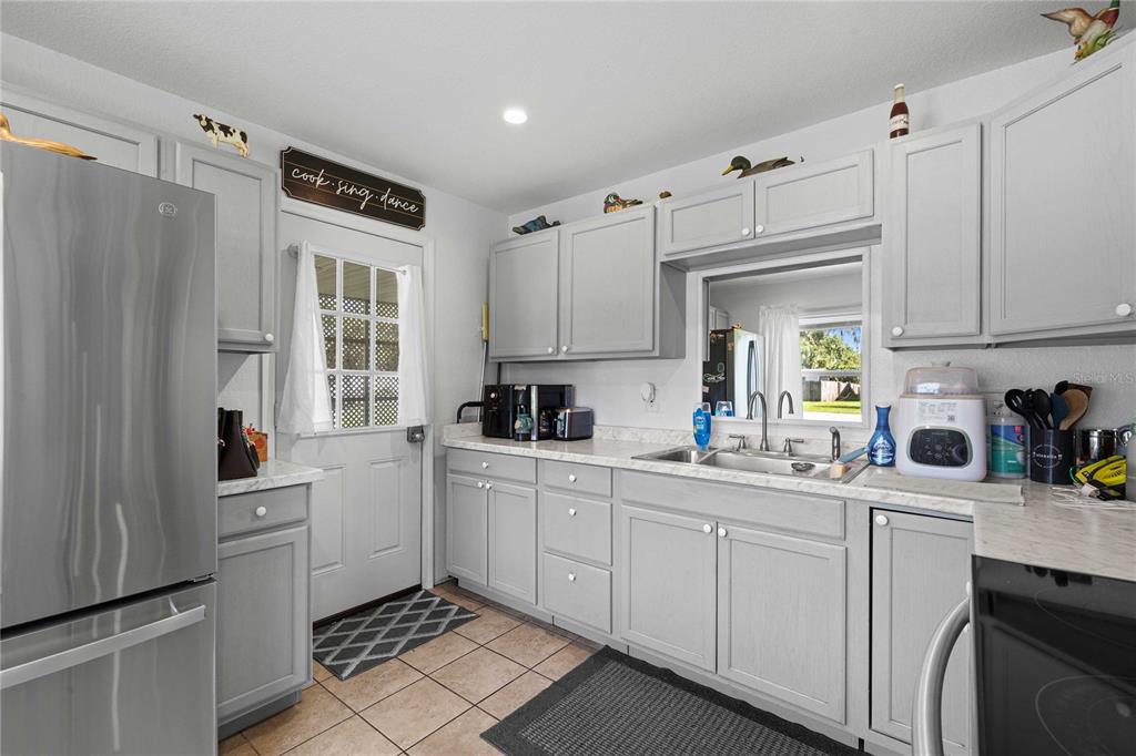 A kitchen features gray cabinets, stainless steel appliances, a white door, and a window — 1056 CR 463, LAKE PANASOFFKEE, FL