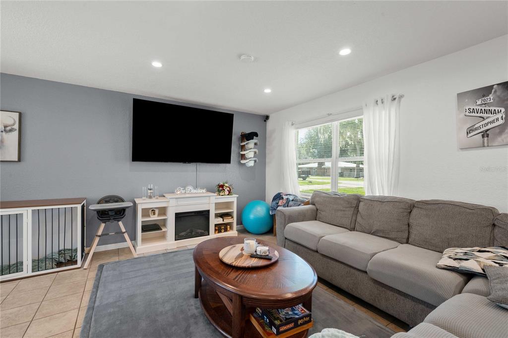 A living room features a gray accent wall with a mounted television, fireplace console, and sofa — 1056 CR 463, LAKE PANASOFFKEE, FL