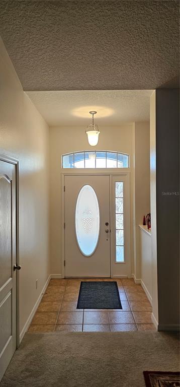 An entryway features a white front door with an oval glass insert, tile flooring, and lighting — 23705 MILFORD DRIVE, EUSTIS, FL