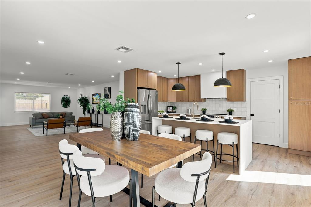 An open-concept kitchen and dining area features wood cabinets, a central island, and light flooring — 900 CARVER STREET, WINTER PARK, FL