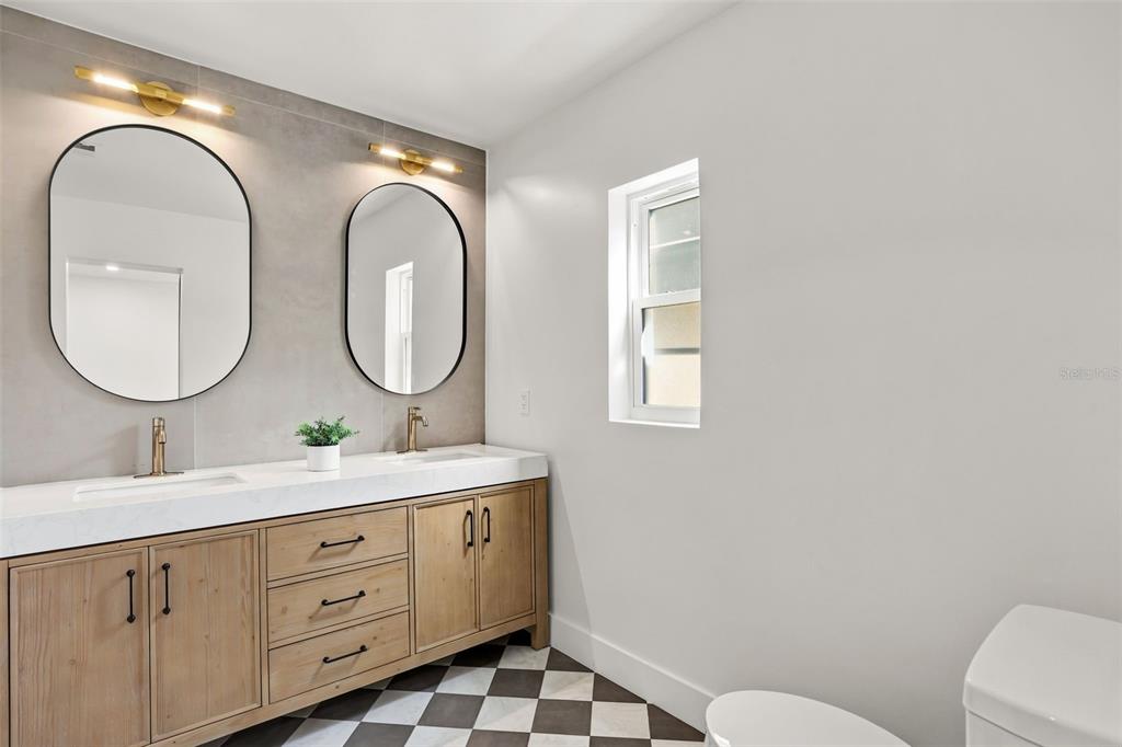 A bathroom features a double vanity with wood cabinets, gold fixtures, and a checkered floor — 900 CARVER STREET, WINTER PARK, FL