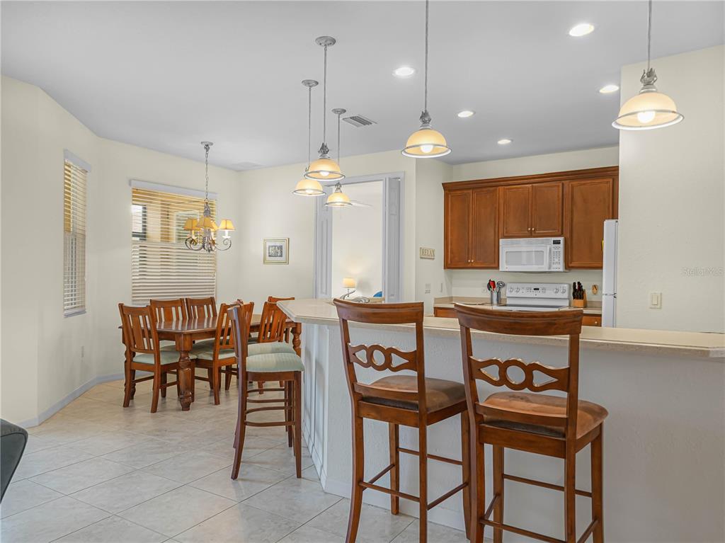 A kitchen with wood cabinets and a breakfast bar overlooks a dining area with tile floors — 5264 GREEN DRIVE, WINTER HAVEN, FL