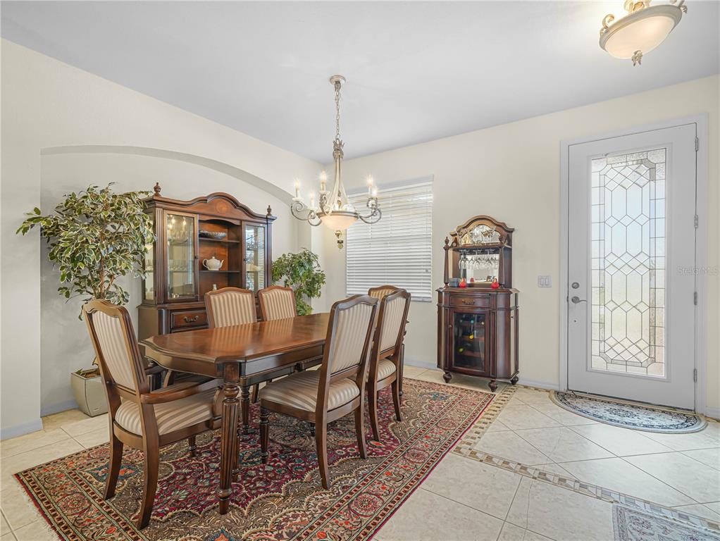 A formal dining room features a wooden table, six chairs, a hutch, and a rug — 5264 GREEN DRIVE, WINTER HAVEN, FL