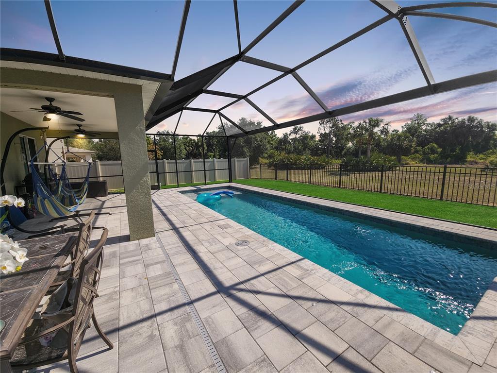 A screened-in patio features a rectangular swimming pool, paver decking, and a hammock — 10106 CYPRESS BRANCH COURT, PUNTA GORDA, FL