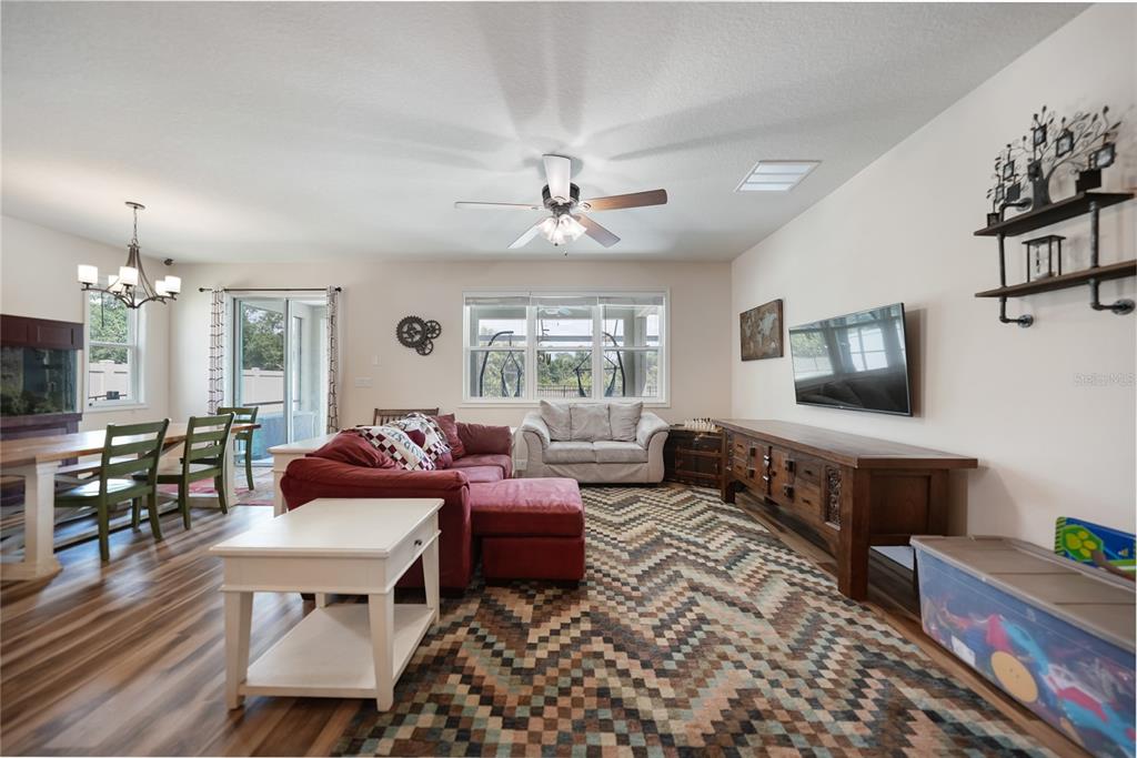 A living room with a red sectional, wood media console, and a patterned area rug — 10106 CYPRESS BRANCH COURT, PUNTA GORDA, FL