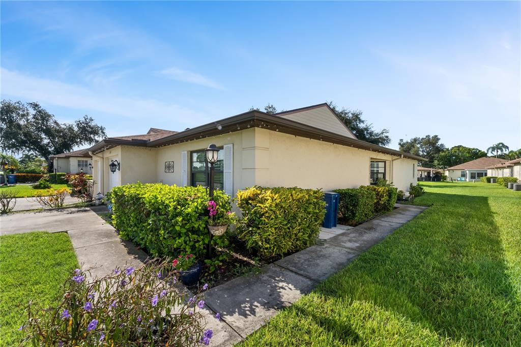 A single-story house with beige stucco walls, a brown roof, and a landscaped front yard — 3312 60TH AVENUE W, BRADENTON, FL