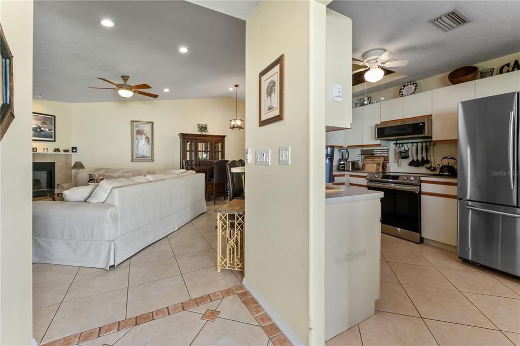 A view from a tiled entryway looking into a living room and an adjacent kitchen — 3312 60TH AVENUE W, BRADENTON, FL