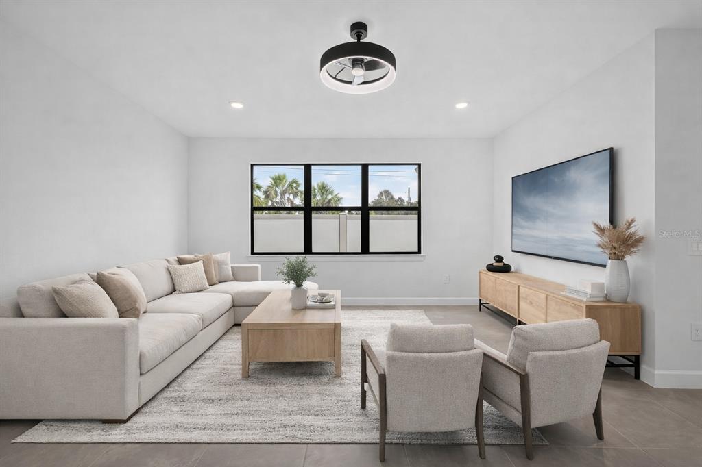 A modern kitchen features white cabinetry, a central island with bar stools, and stainless appliances — 12307 WIGEON DRIVE, BRADENTON, FL
