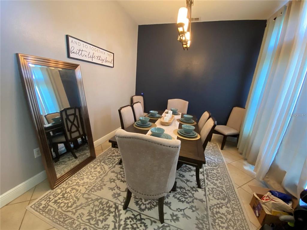A dining room features a dark accent wall, a large floor mirror, and a table set — 1953 THE OAKS BOULEVARD, KISSIMMEE, FL
