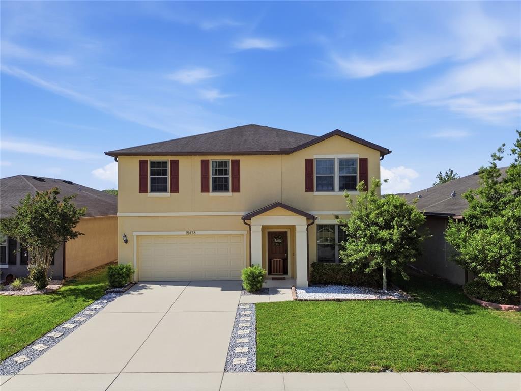 The backyard of a two-story yellow house features a lawn, white vinyl fencing, and toys — 15476 STONE HOUSE DRIVE, BROOKSVILLE, FL