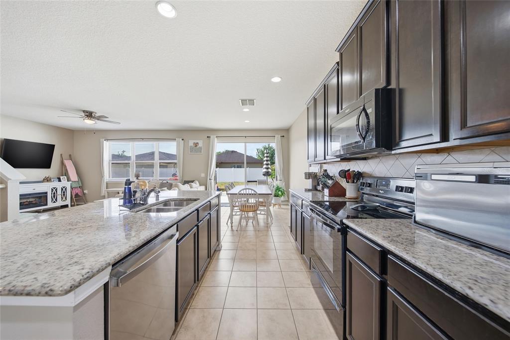 An open-concept living room and kitchen featuring wood-look flooring, a sectional sofa, and bar seating — 15476 STONE HOUSE DRIVE, BROOKSVILLE, FL