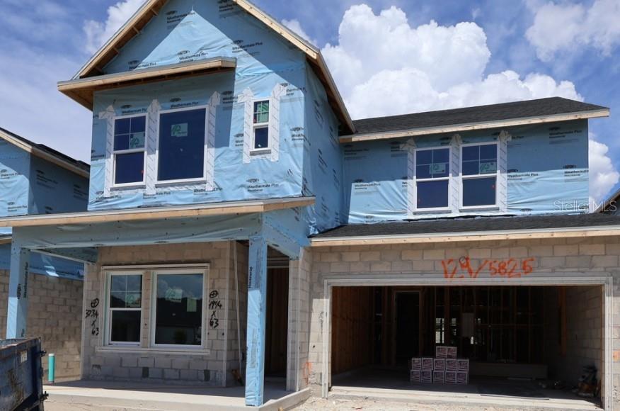 A two-story house under construction features blue weather-resistant house wrap and a concrete block exterior — 5825 NATIVE OAK STREET, MOUNT DORA, FL