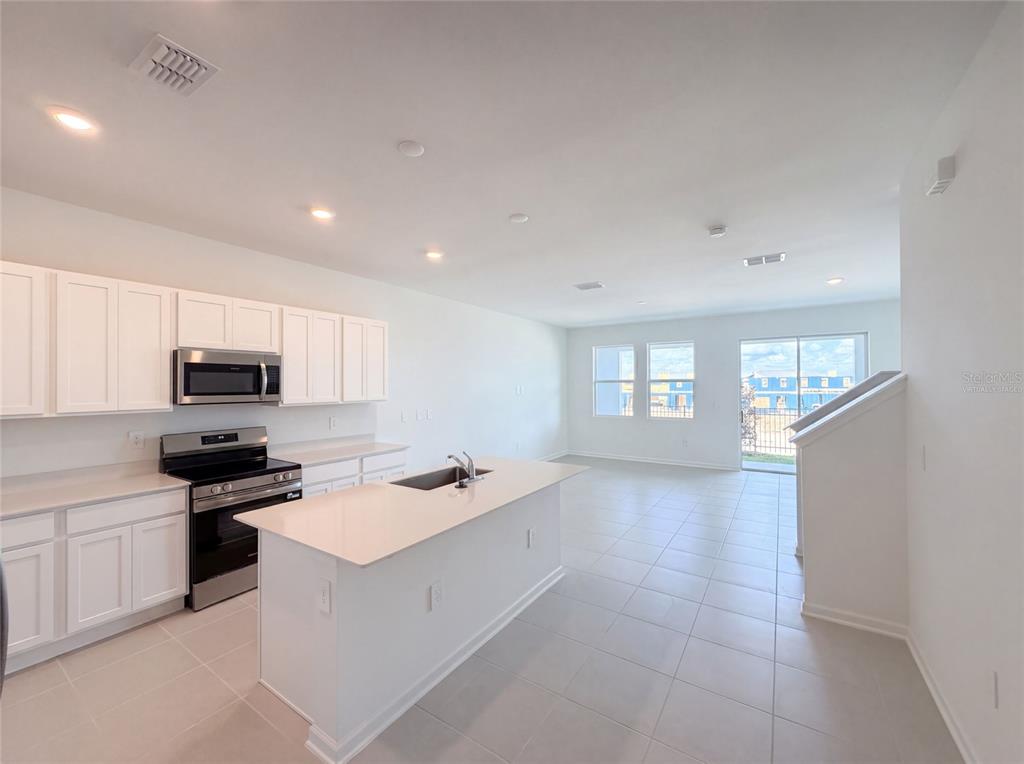 A kitchen with white cabinets, stainless steel appliances, and a central island with a sink — 3110 KURTZ TERRACE, DAVENPORT, FL