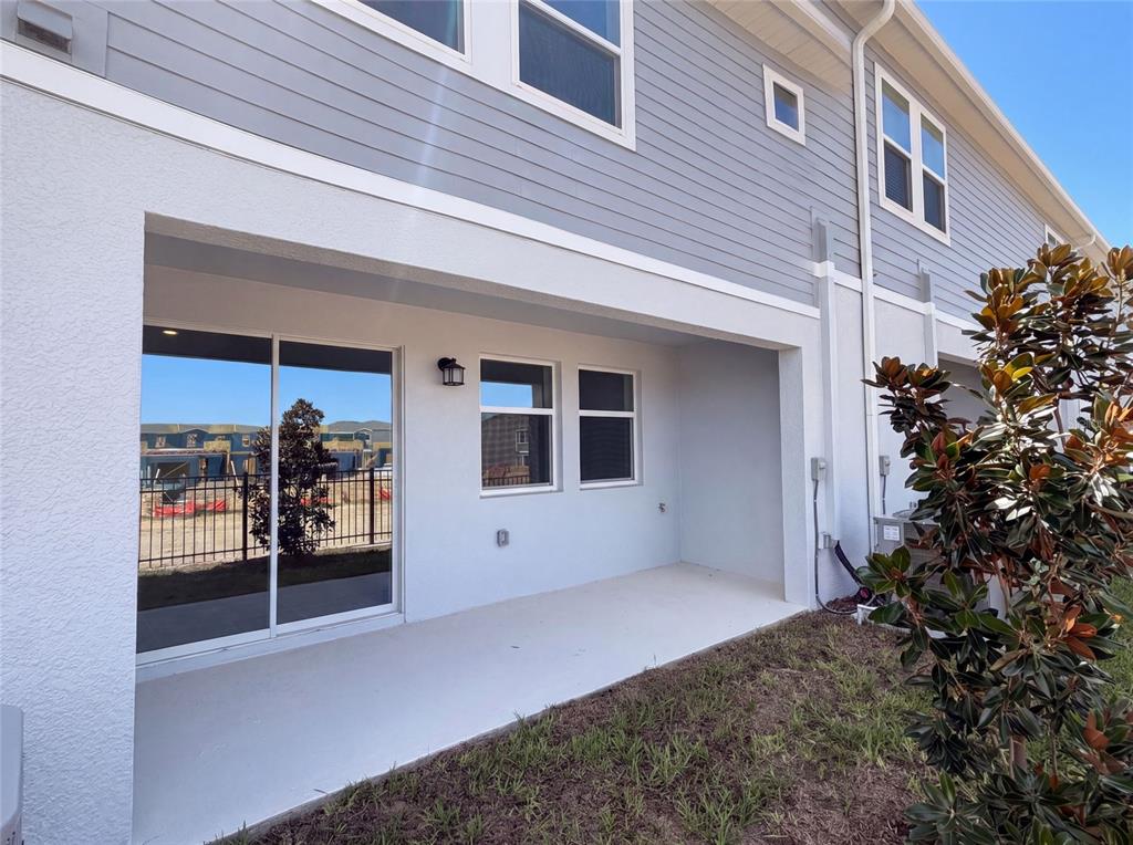 A covered concrete patio sits outside a two-story house with gray siding and white trim — 3110 KURTZ TERRACE, DAVENPORT, FL