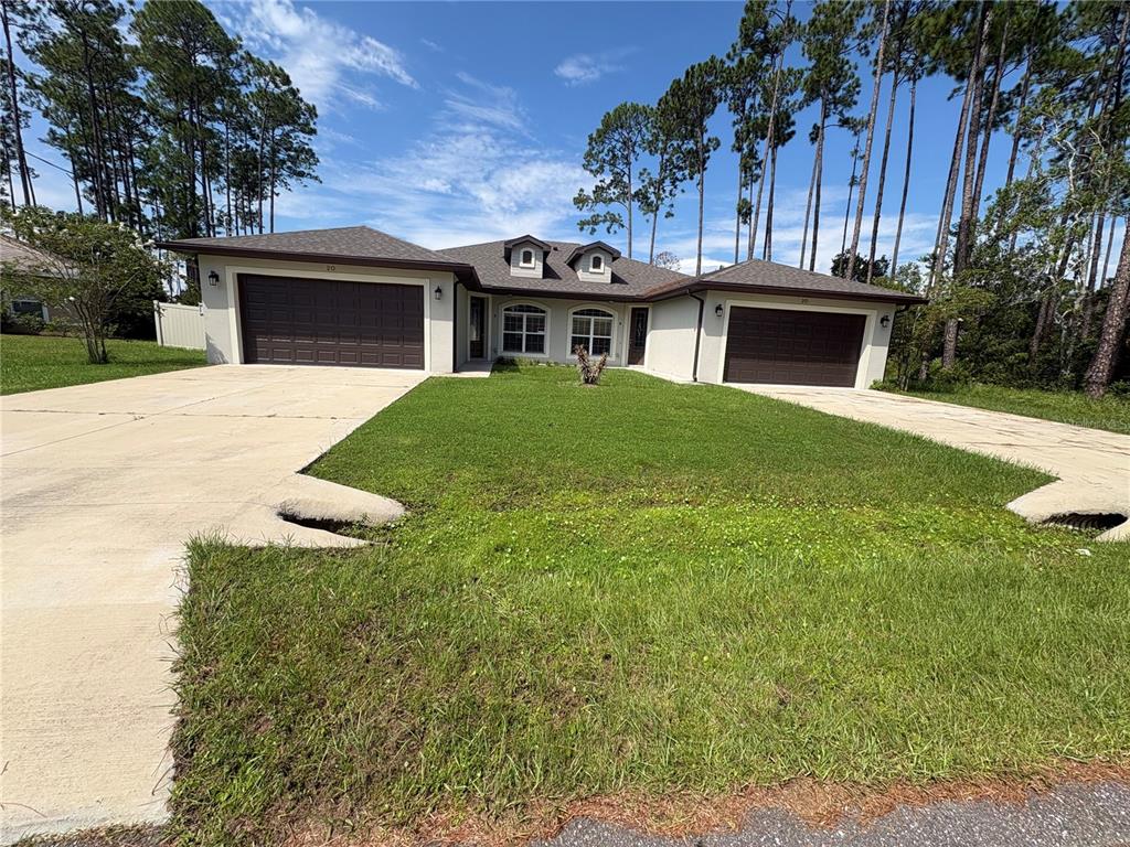A single-story house with two garages, a central entrance, and a lawn under a blue sky — 20 ETON LANE UNIT A & B, PALM COAST, FL