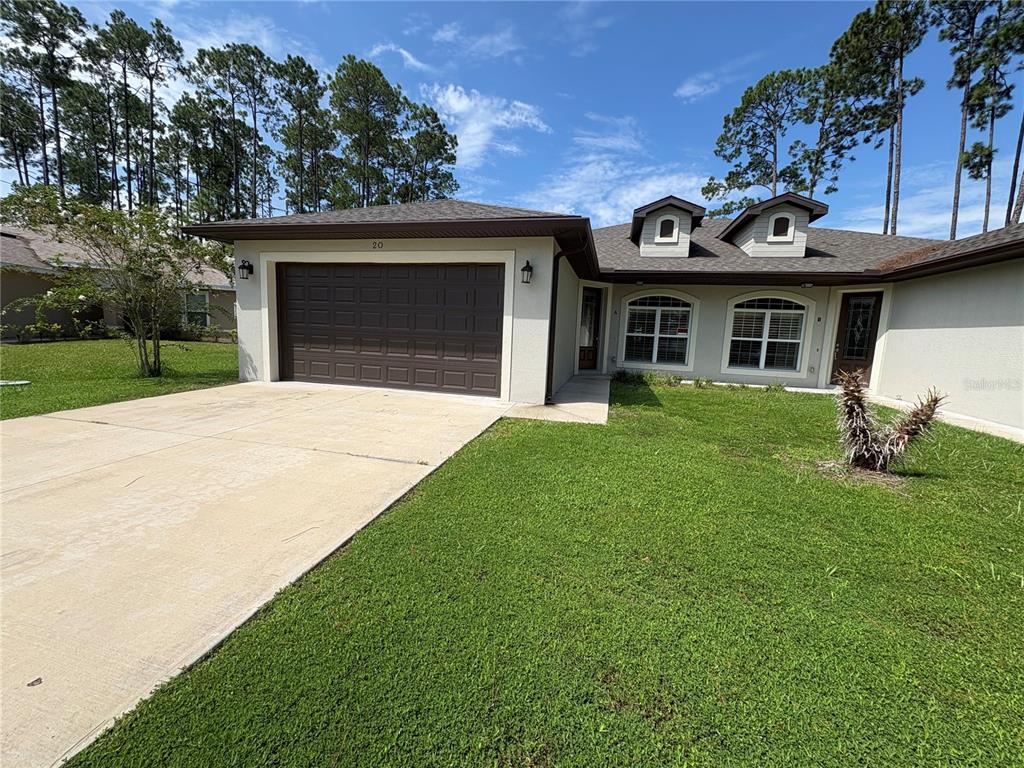 A single-story duplex with a tan stucco exterior, two garage doors, and two front entrances — 20 ETON LANE UNIT A & B, PALM COAST, FL