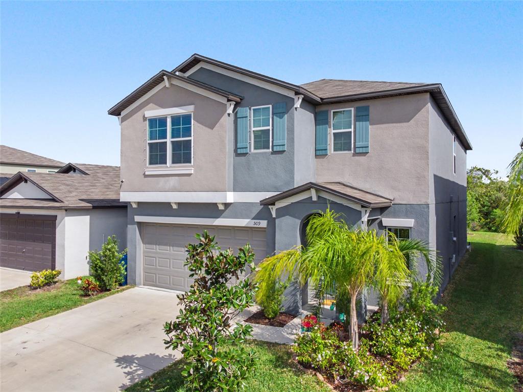A two-story house with a gray stucco exterior, a two-car garage, and blue shutters — 509 ROYAL EMPRESS DRIVE, RUSKIN, FL