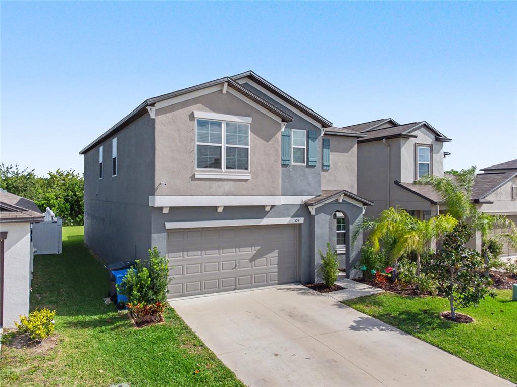 A two-story suburban house with a gray stucco exterior, a two-car garage, and a driveway — 509 ROYAL EMPRESS DRIVE, RUSKIN, FL