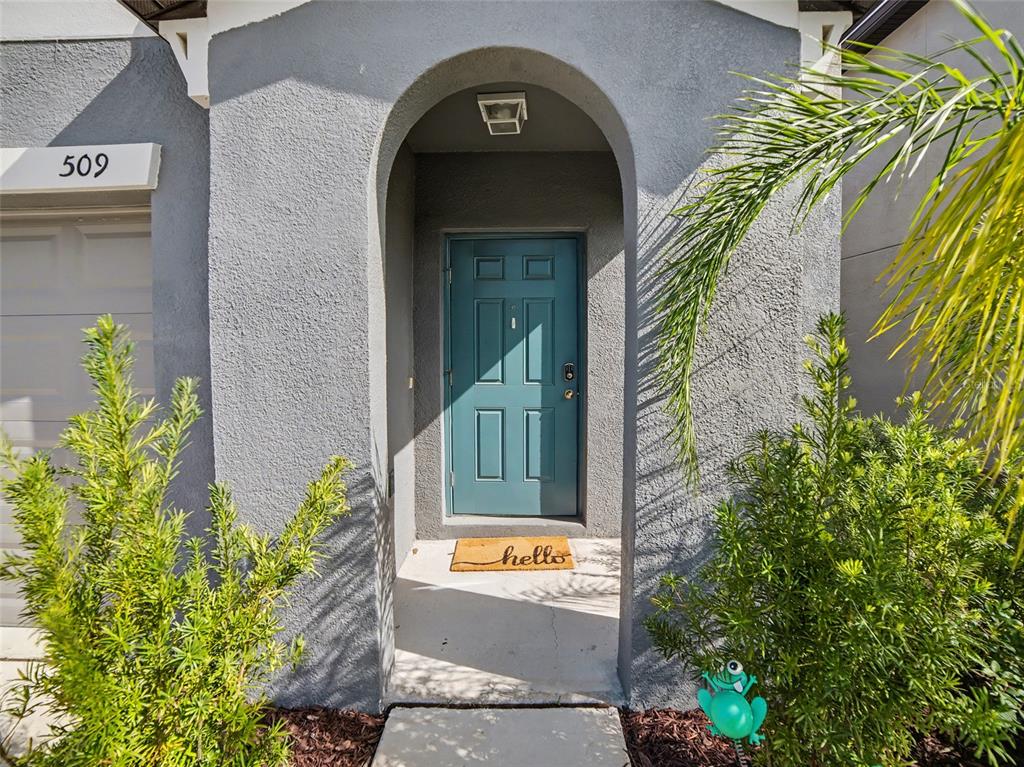 The exterior of a house features a gray arched entryway with a teal front door — 509 ROYAL EMPRESS DRIVE, RUSKIN, FL