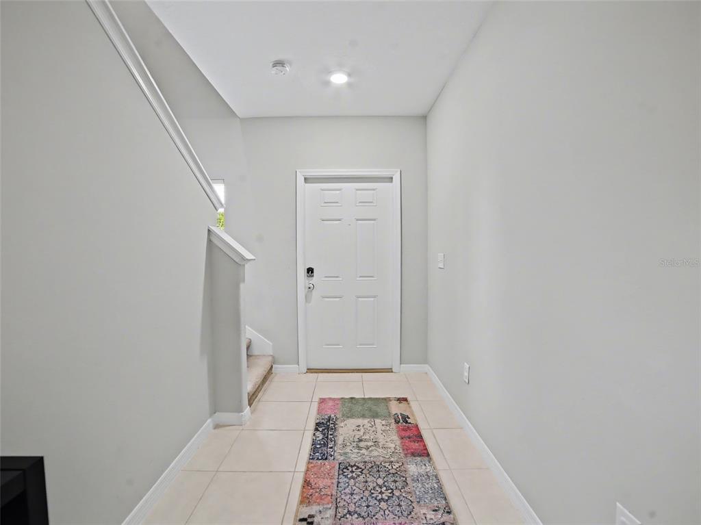 An entryway features light-colored tile flooring, a white front door, and a staircase with carpet — 509 ROYAL EMPRESS DRIVE, RUSKIN, FL