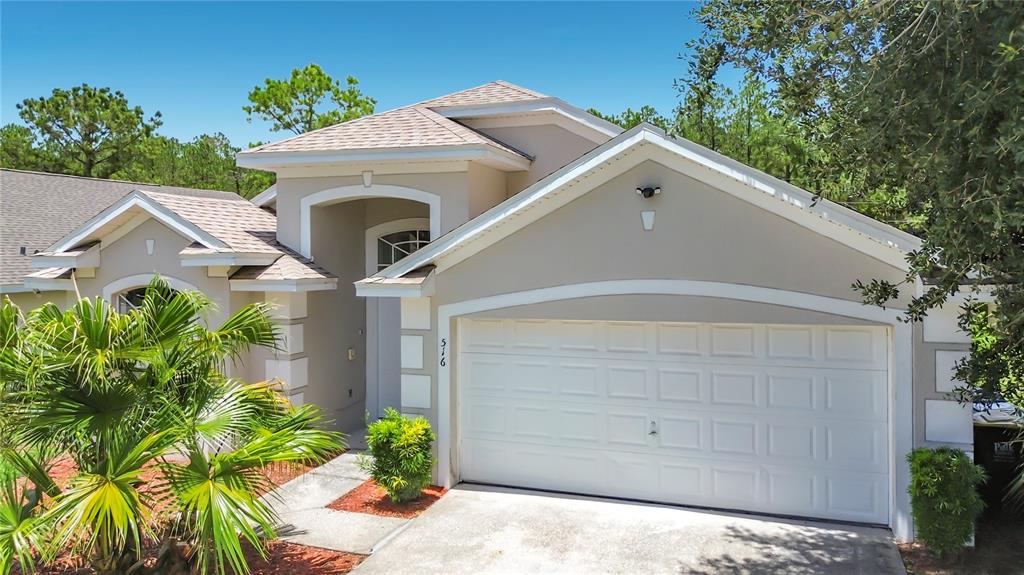 A white double front door with a transom window sits between two stucco pillars — 516 PINE CONE DRIVE, DAVENPORT, FL