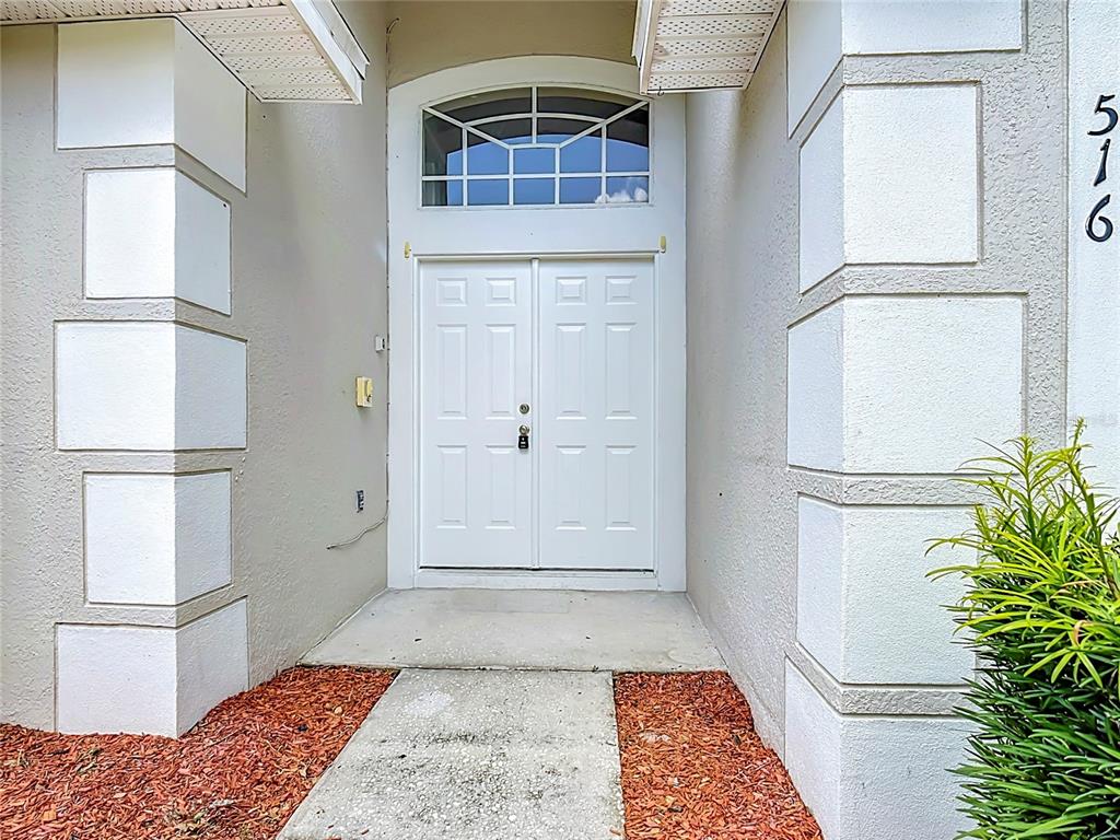 A tiled entryway features white double doors with a transom window above — 516 PINE CONE DRIVE, DAVENPORT, FL