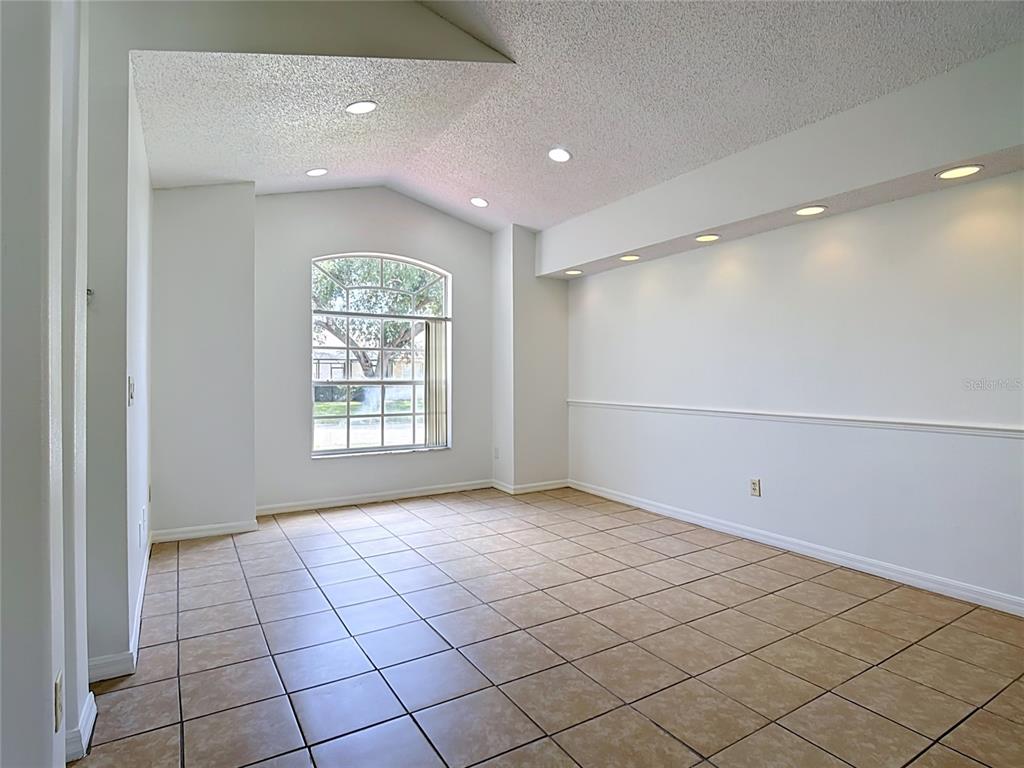 A bright living room features light-colored furniture, a wooden coffee table, and a large window — 516 PINE CONE DRIVE, DAVENPORT, FL